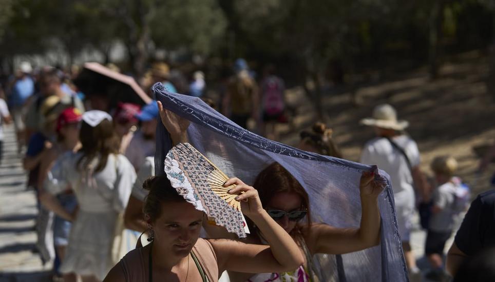 Touristen in Athen suchen Schutz vor der Sonne. Bild: Petros Giannakouris/AP