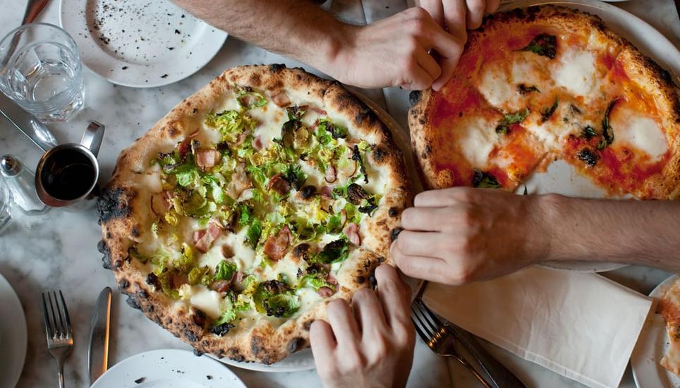 Zwei für vier: Zum Teil erheben Restaurants Gebühren fürs Pizza-Teilen. Bild: Michael Berman / Getty