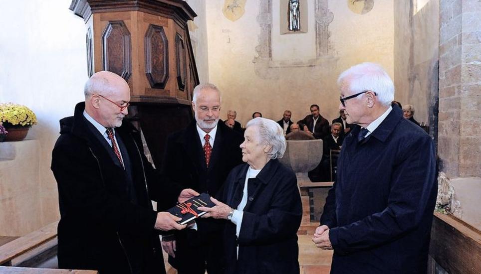 Michael Psczolla, Gunnar Lang und Josef Zumbühl (v. l. n. r.) überreichen der Ehrenbürgerin Carina Schweizer als Geschenk das vor Kurzem erschienene Buch «Baugeschichte der Bergkirche St. Michael». Bild Bruno Bührer