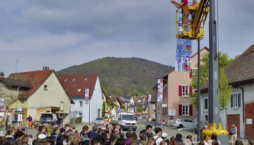 Werklehrer Andreas Flubacher (im Lastkorb) hat soeben die letzte der knapp 20 Fahnen aufgehängt – zur grossen Freude der Beringer Schüler. Bild: Theo Kübler