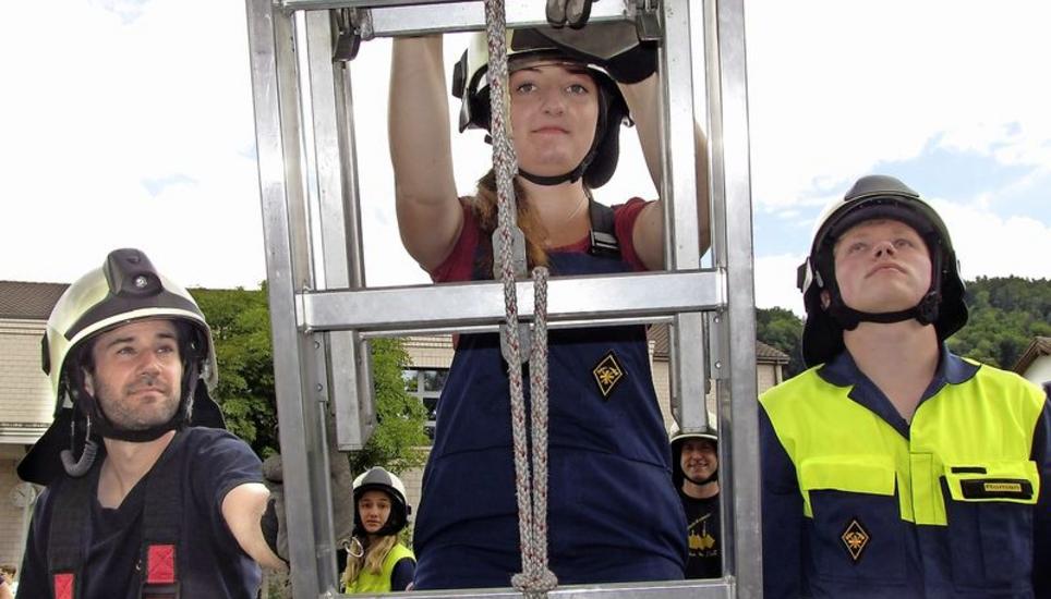 Immer schön vorsichtig: Hier klettert eine junge Dame bei der Feuerwehrübung die Leiter hoch. Dabei wird sie von ihren Kollegen gesichert. Bild: Ernst Hunkeler