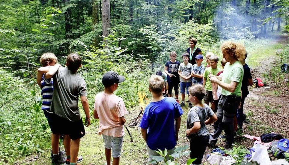 Gespannt lauschen die Kinder den Anweisungen und Erklärungen von Kursleiter Stephan Kelz. Weil sie es alle geschafft haben, ein Feuer zu machen, geht das Kursprogramm weiter. Bild: Maximilian Wiggenhauser