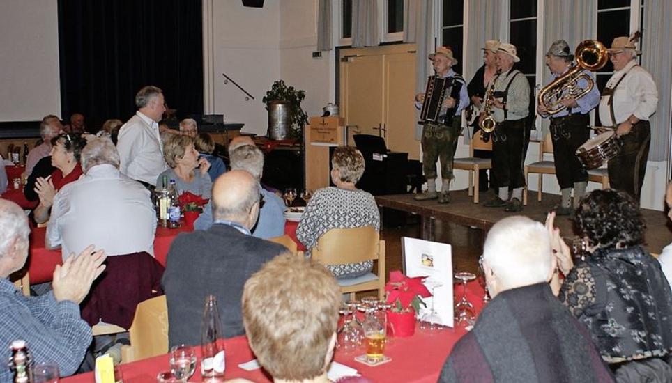 Raclette-Stubete-Organisator Sepp Helbling (links im Bild, stehend) auf dem Weg, die Talheimer Strassenmusikanten aus dem Hegau anzukündigen. Bild: Susanne Feld