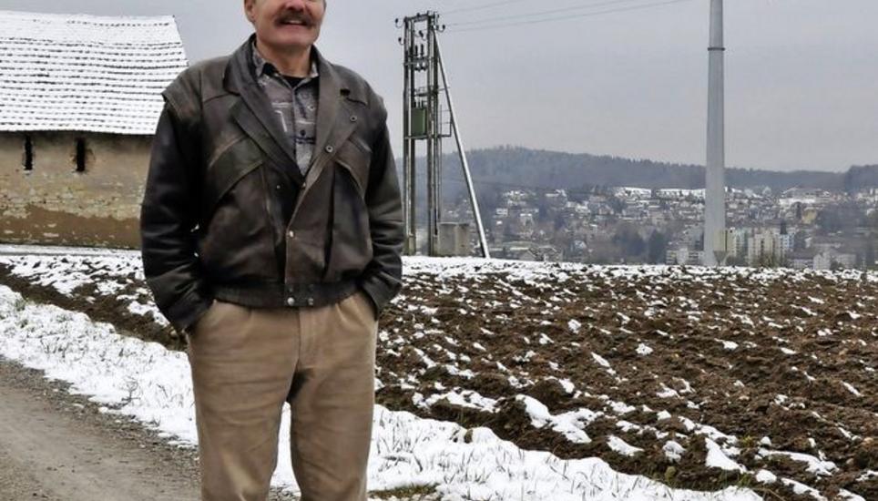 Der Präsident der Genossenschaft Windland, Jürg Meier, und das neue Windrad auf Allenwinden. Bild: Mark Gasser