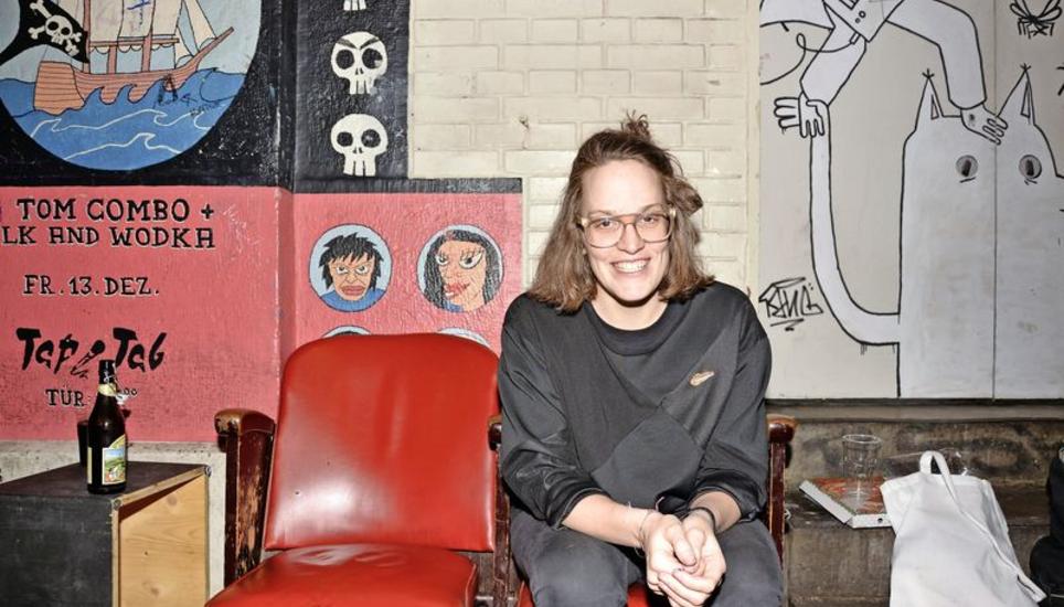Die Künstlerin Kooni macht es sich vor dem Musikraum TapTab bequem: Auf der linken Seite prangt ein Werk von Milk + Wodka, auf der Tür rechts von Kooni sind ihre eigenen Malereien zu sehen. Bild: Miriam Barner