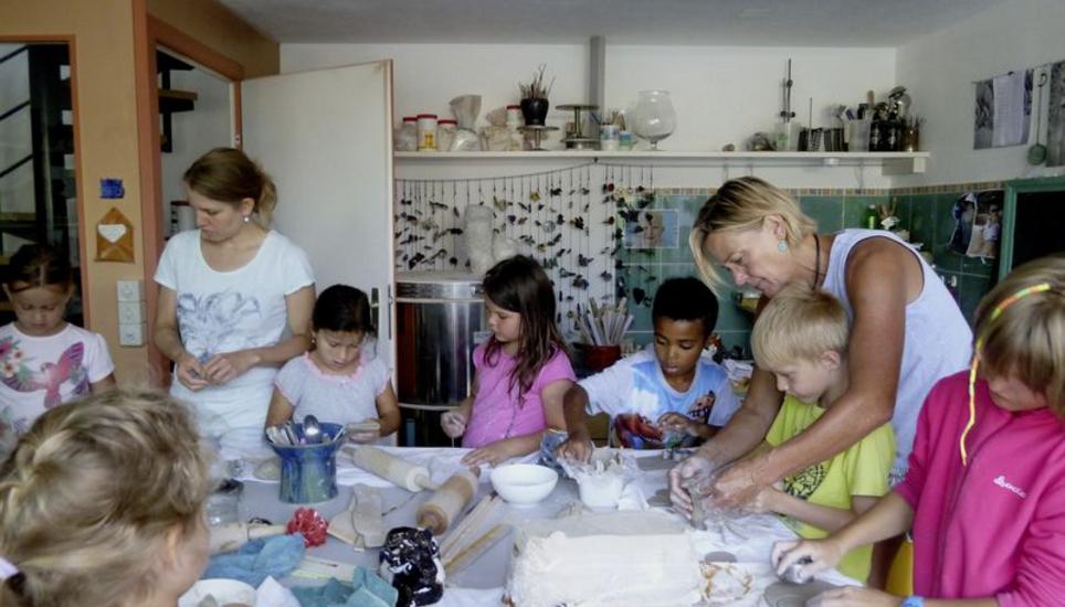 Edith Wäspi (Zweite von rechts) und ihre Tochter Fabienne (Zweite von links) basteln mit den Kindern Kühe aus Ton. Bild: Ursula Junker