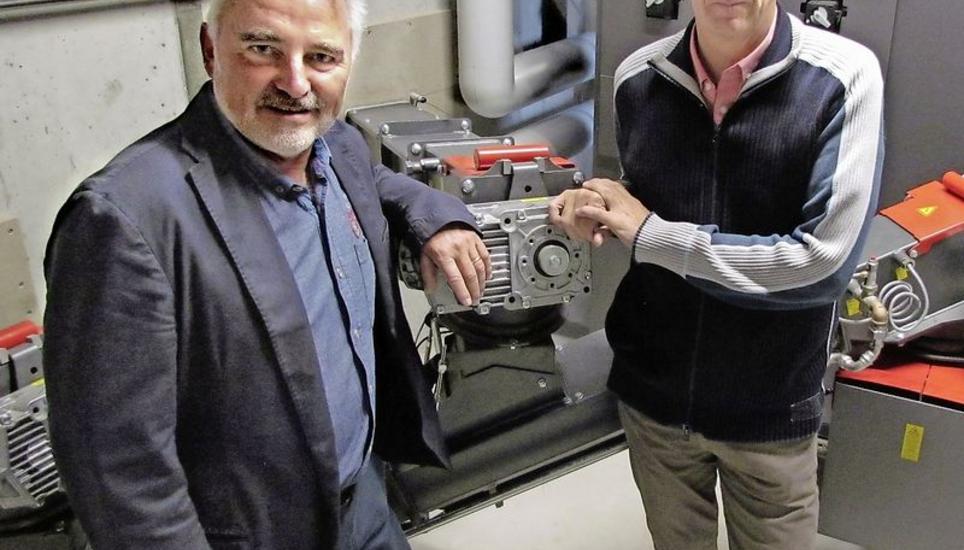 Gemeindepräsident Claus Ullmann (links) und Projektleiter Philippe Rimbeaux vor einem der neuen Heizöfen mit den Anschlüssen der Schnitzelkanäle. Bild: Ernst Hunkeler