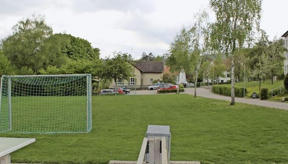 Der Neubau für Kindergärten und erste Primarstufen käme auf die leer stehende Wiese. Im Hintergrund sieht man den alten Kindergarten, der rückgebaut werden soll. Bilder: Andreas Grossmann
