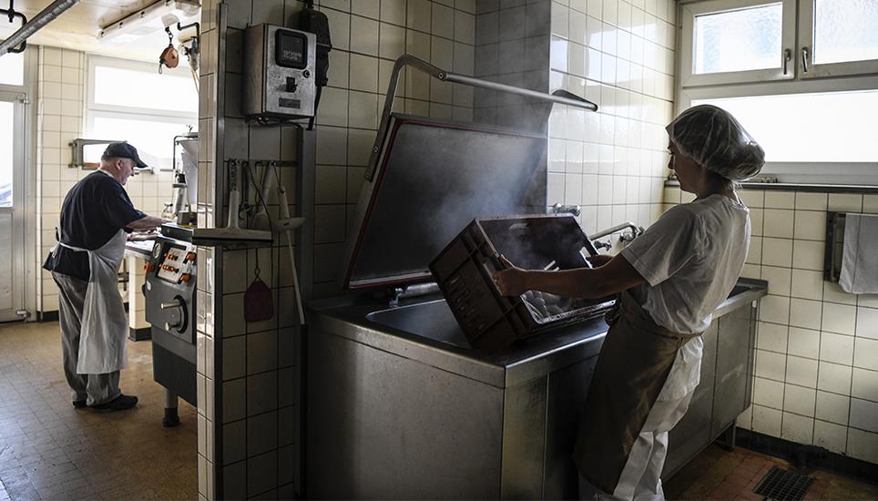 Während Willi Pfistner noch Würste aus der Spritzmaschine lässt, ist Kristina Zerr schon beim Abbrühen der ersten Ladung. Bild: Melanie Duchene