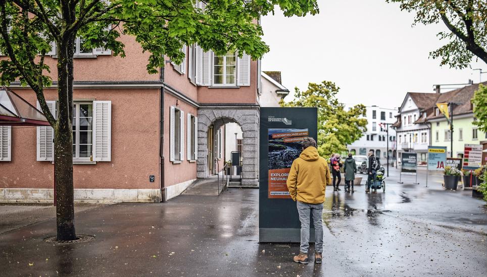 Das Neuhauser Ortsmarketing hat vor Kurzem den Explorer Trail, der hier auf einem Plakat vor dem Gemeindehaus beworben wird, ins Leben gerufen. Bild: Melanie Duchene