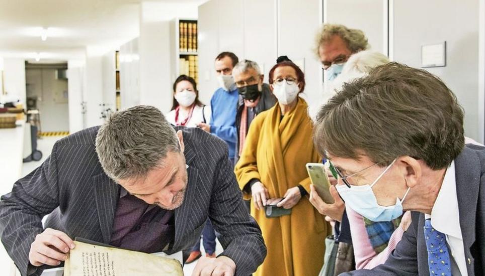 Stadtbibliothekar Oliver Thiele zeigt den Gästen, darunter Stadtrat Raphaël Rohner, die wertvolle Handschrift. Bild: Jeannette Vogel