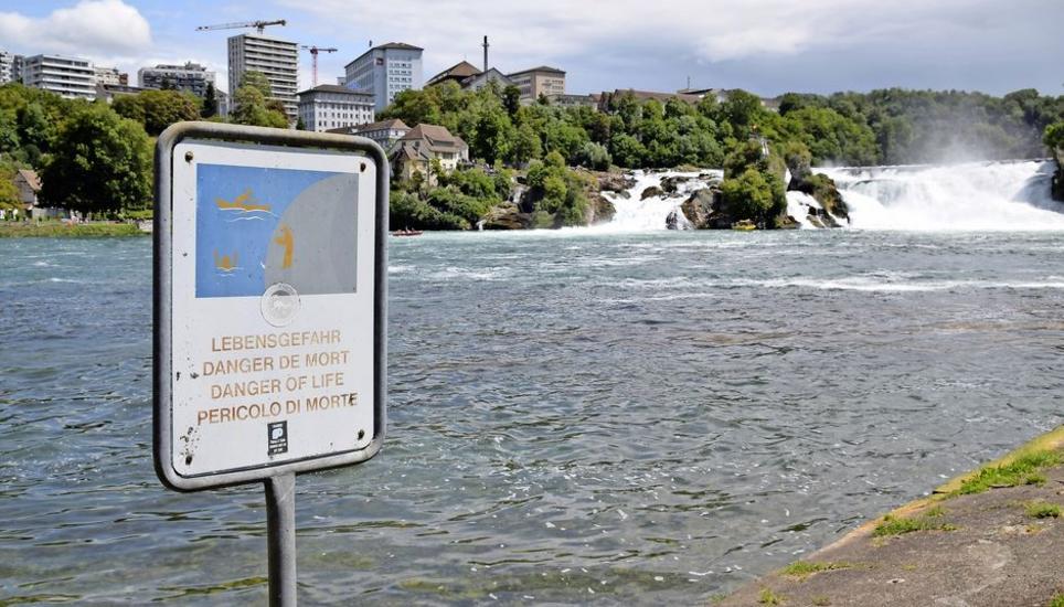Bei der einzigen Treppe, die direkt zum Rheinfallbecken führt, weist eine Tafel auf die Gefahren beim Baden hin. Bild: Saskia Baumgartner