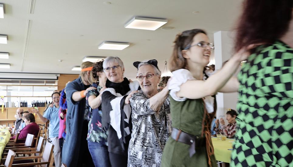 Hildegard Hatt (mit Katzenohren), seit 64 Jahren treue SN-Abonnentin, hält sich an den Schultern von Sara Höhener fest. Bild: Lucas Blumer