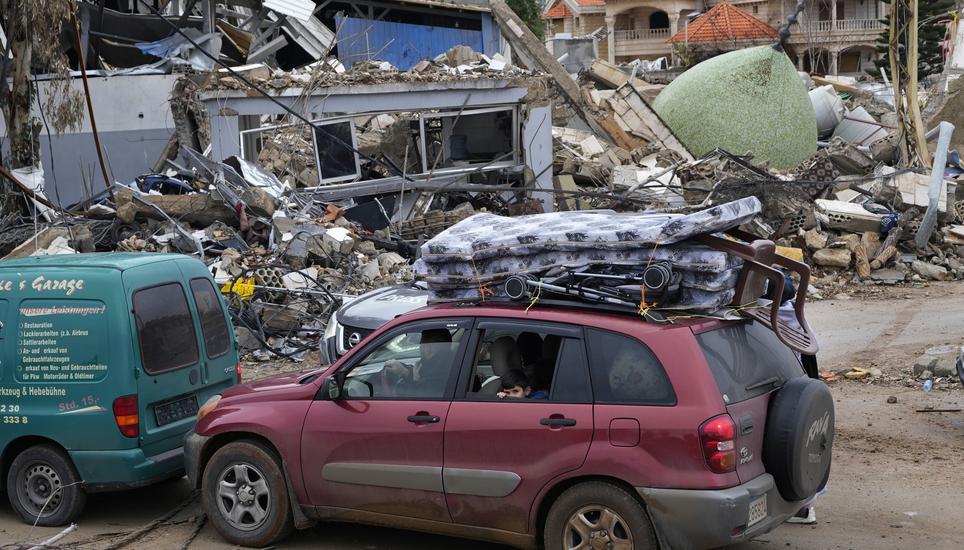 Displaced residents returning to their village, sit in their car with belonging as they pass in front of a destroyed mosque, in the town of Bint Jbeil, southern Lebanon, following a ceasefire between Israel and Hezbollah that went into effect on Wednesday