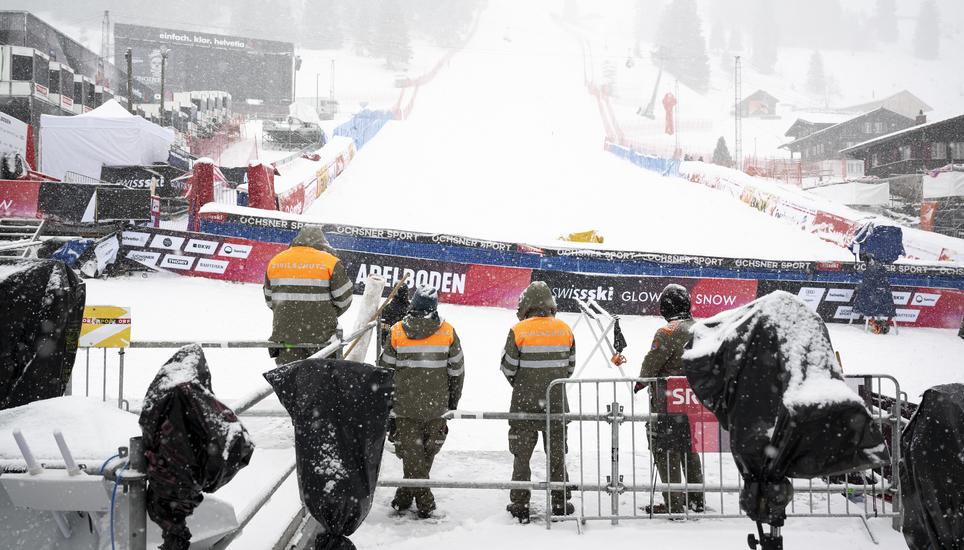 Civil protection members observe a minute of silence in memory of the victims during the national day of mourning following the deadly fire at the "Le Constellation" bar, one day prior to the FIS Alpine Ski World Cup Giant slalom, in the finish area, in A