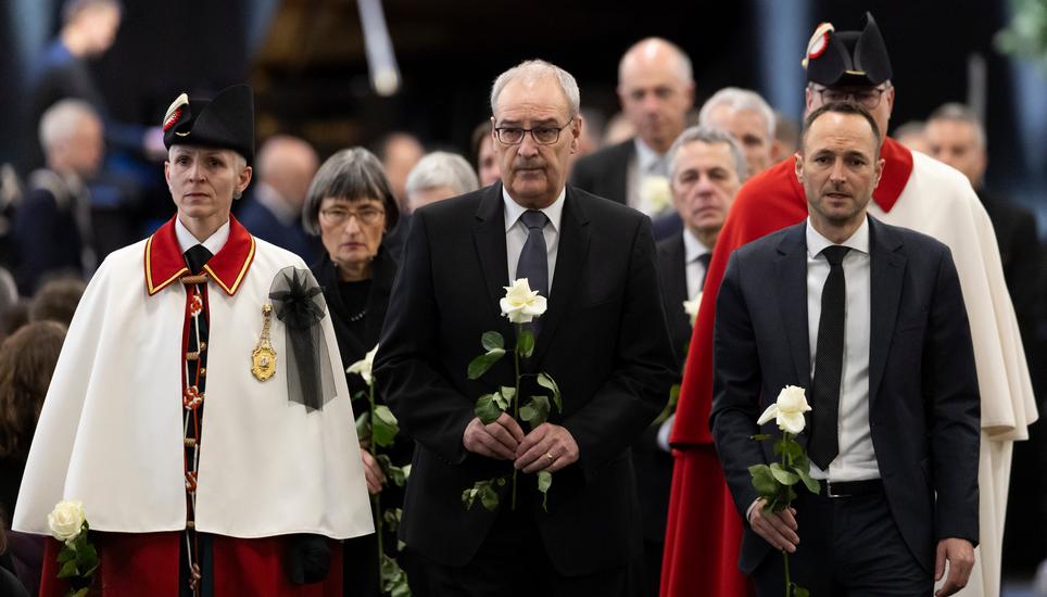 Swiss President Guy Parmelin, center, and Mathias Reynard, state councillor and president of the Council of State of the Canton of Valais, hold white roses at the end of the official commemorative ceremony for the victims of the deadly fire at the "Le Con
