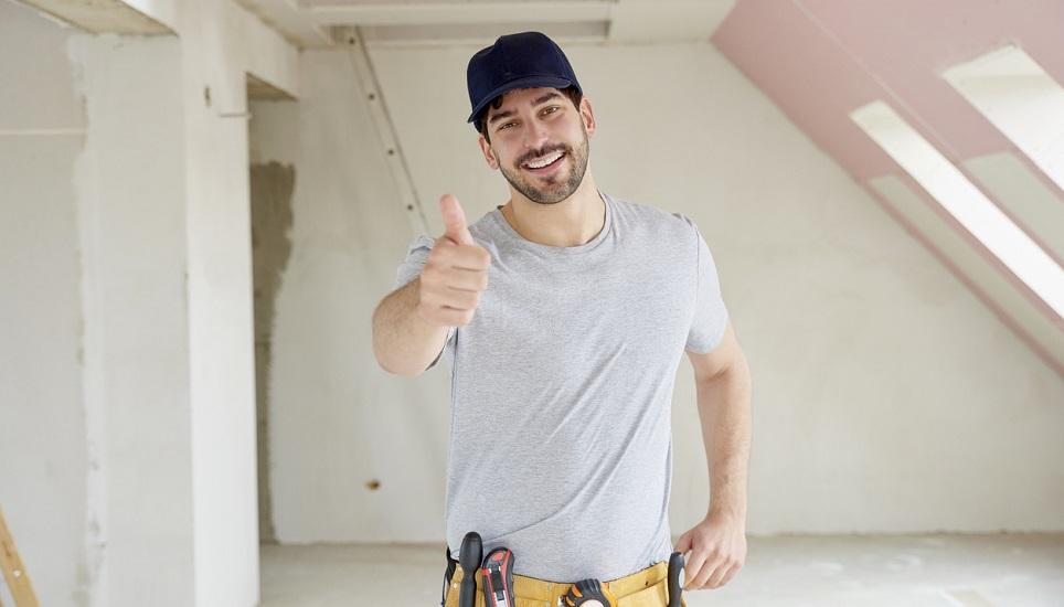 Portrait of young handyman giving thumbs up while standing at construction site. 