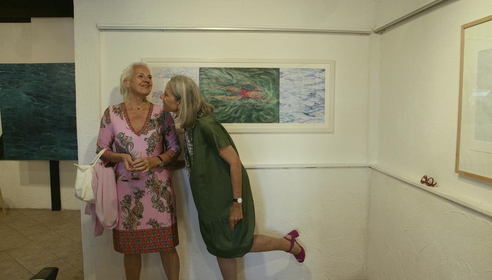 Künstlerin Sibylle Badertscher (rechts) erklärt einer Besucherin der Vernissage, wie sie im Winter ins Wasser steigt. Bild: Wolfgang Schreiber