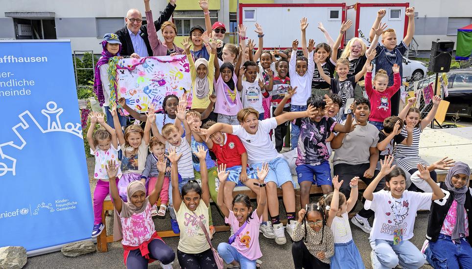 Die Kinder feierten die Übergabe des Unicef-Labels durch Cyrill Tait an Christine Thommen (beide oben links) begeistert mit. Bilder: Michael Kessler