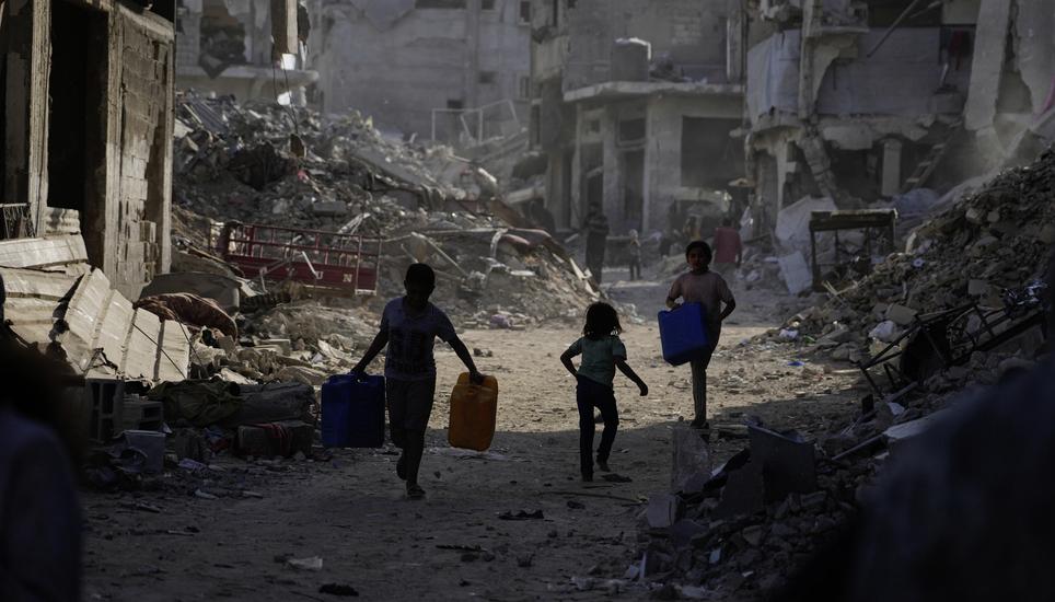 Palestinians carry jerrycans to collect water from a truck amid the destruction caused by the Israeli air and ground offensive in Gaza City, Thursday, Oct. 16, 2025. (AP Photo/Jehad Alshrafi)