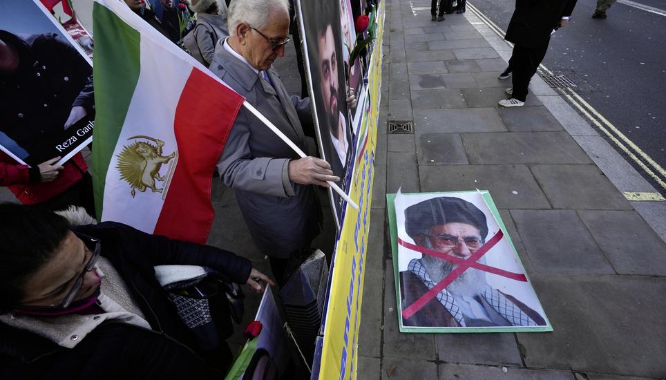 Protesters hold up placards and flag as they demonstrate outside the Downing Street, in London, Wednesday, Jan. 14, 2026. (AP Photo/Kin Cheung)