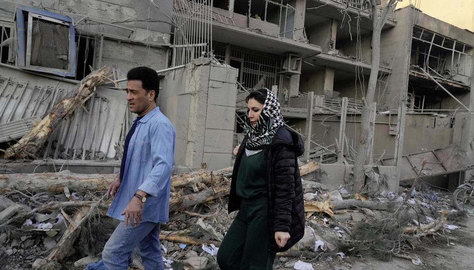 People walk past buildings damaged during a strike on a police station during ongoing, joint U.S.-Israeli military attacks in Tehran, Iran, Monday, March 2, 2026. (AP Photo/Vahid Salemi)