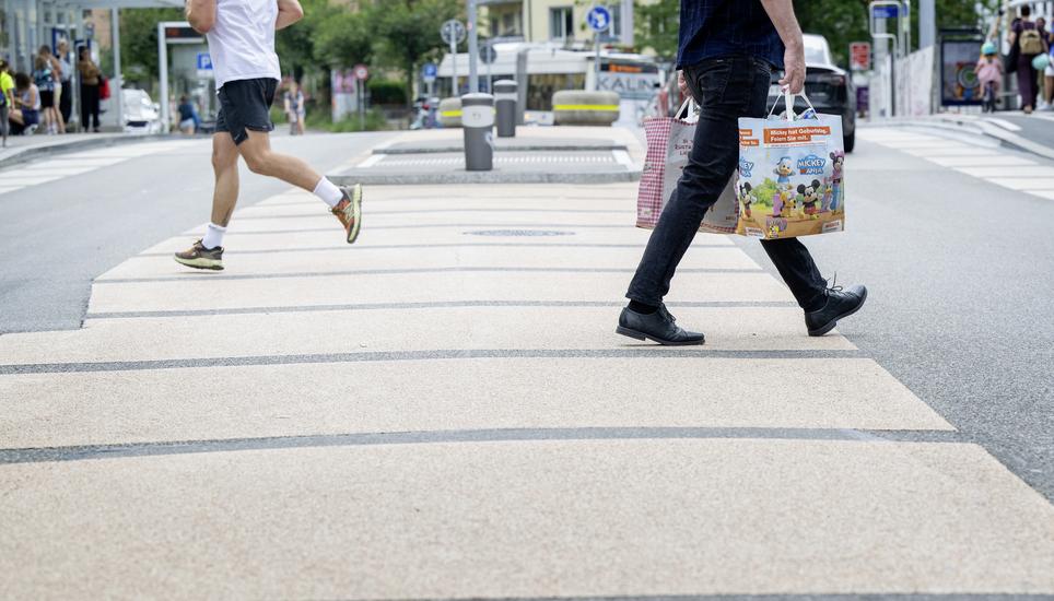 Passanten ueberqueren den Mehrzweckstreifen Nordbruecke beim Roeschibachplatz, fotografiert am Montag, 15. Juli 2024 in Zuerich Wipkingen. Der  Mehrzweckstreifen ermoeglicht es ueberall die Strasse zu Queren, da es in zwei Etappen moeglich ist.  (KEYSTONE