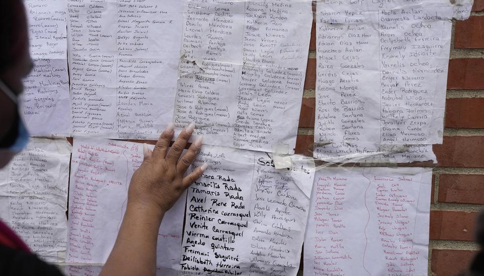 A woman looks for her relatives' names on lists of missing people after deadly earthquakes in La Guaira, Venezuela, Sunday, June 28, 2026. (AP Photo/Matias Delacroix)
