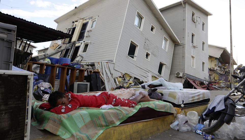 A boy sleeps outside earthquake-damaged homes in Catia La Mar, Venezuela, Sunday, June 28, 2026. (AP Photo/Pedro Mattey)