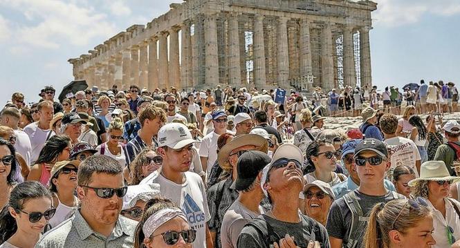 Atop the Acropolis ancient hill, tourists visit the Parthenon temple, background, in Athens, Greece, Tuesday, July 4, 2023. Crowds are packing the Colosseum, the Louvre, the Acropolis and other major attractions as tourism exceeds 2019 records in some of 