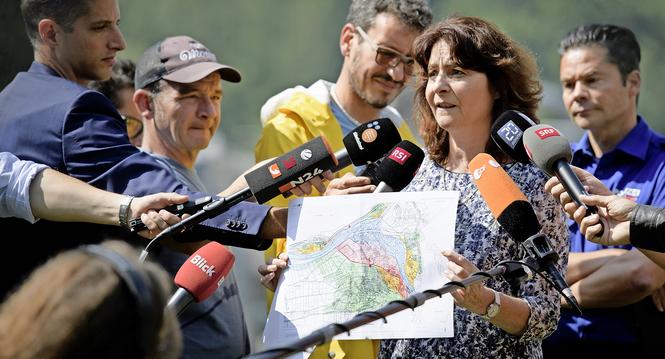 Anna Giacometti, mayor of the community Bregaglia, shows a map of Bondo, with Roman Ruegg, spokesman police Graubuenden in the background, in Bondo, Graubuenden in South Switzerland, on Friday, August 25, 2017. The village had been hit by a massive landsl