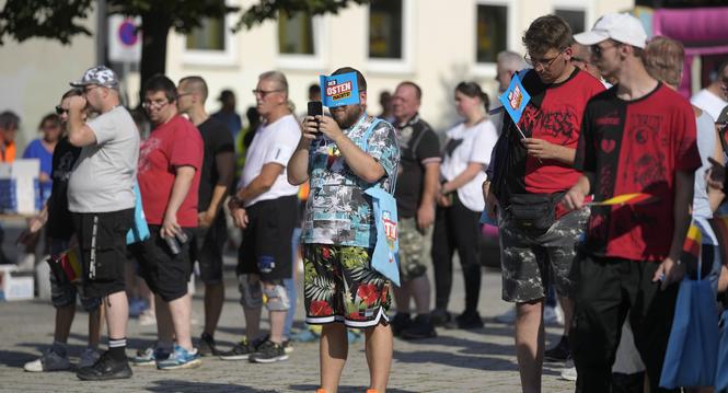 Supporters of the far-right Alternative for Germany party, or AfD, hold small paper flags that read: "The East Does it", as they attend an election campaign rally of the party for upcoming state elections in Suhl, Germany, Tuesday, Aug. 13, 2024. In the f