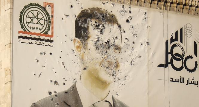 An image of Syrian President Bashar Assad, riddled with bullets, is seen on the facade of the provincial government office in the aftermath of the opposition's takeover of Hama, Syria, Friday, Dec. 6, 2024. (AP Photo/Omar Albam)