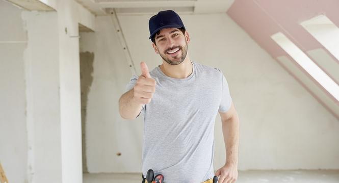 Portrait of young handyman giving thumbs up while standing at construction site. 