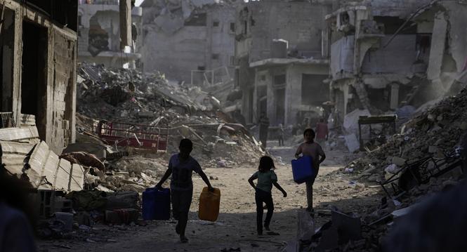 Palestinians carry jerrycans to collect water from a truck amid the destruction caused by the Israeli air and ground offensive in Gaza City, Thursday, Oct. 16, 2025. (AP Photo/Jehad Alshrafi)