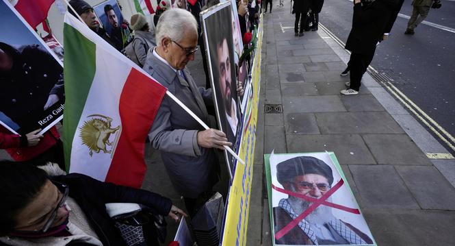 Protesters hold up placards and flag as they demonstrate outside the Downing Street, in London, Wednesday, Jan. 14, 2026. (AP Photo/Kin Cheung)