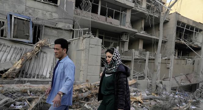 People walk past buildings damaged during a strike on a police station during ongoing, joint U.S.-Israeli military attacks in Tehran, Iran, Monday, March 2, 2026. (AP Photo/Vahid Salemi)
